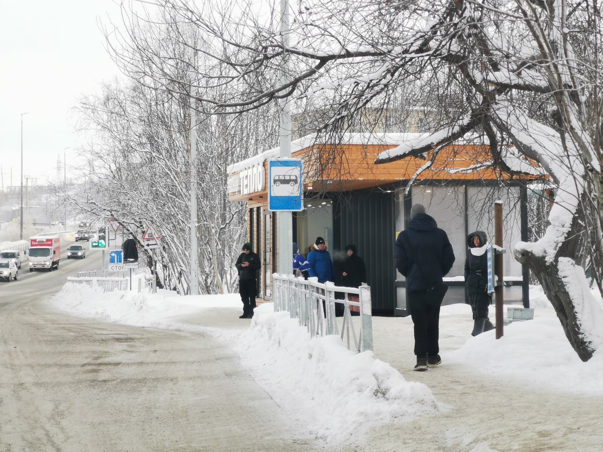 Люди стоят на остановке зимой