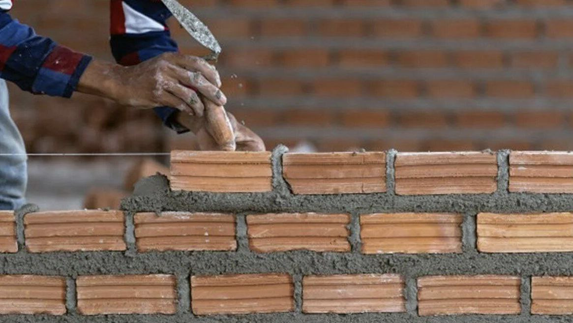 руки мастера укладывают кирпич