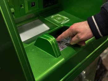 Мужчина снимает наличные в банкомате.