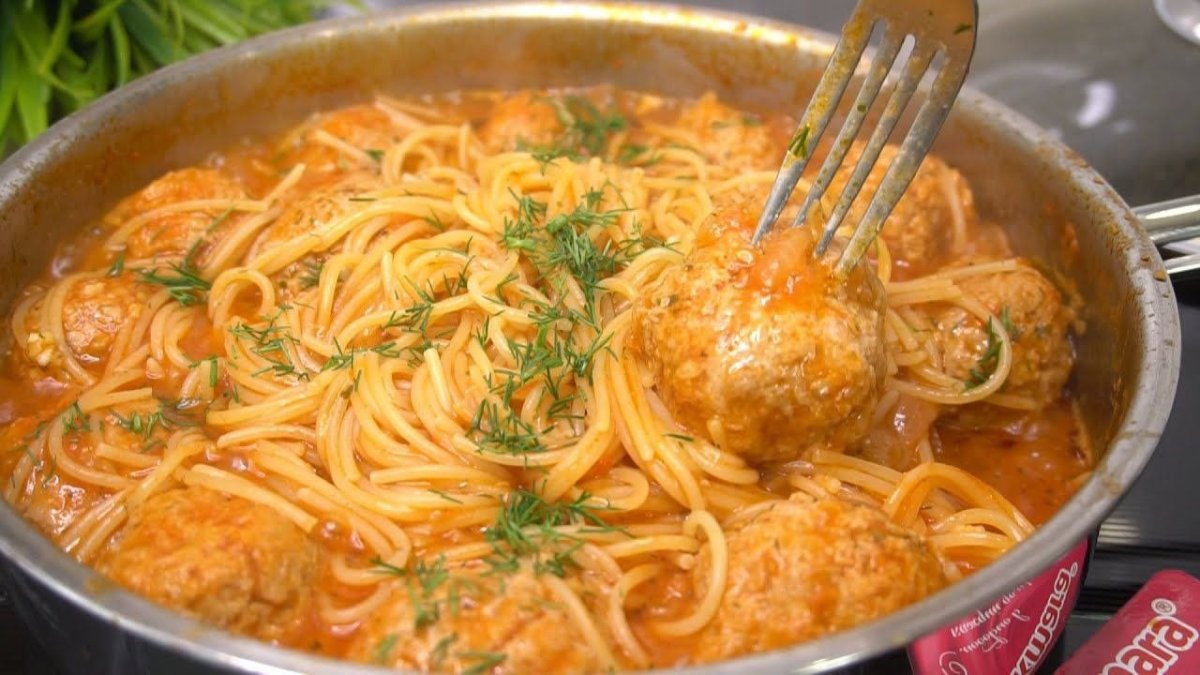 сковорода, полная соуса, в котором видны спагетти и тефтели
